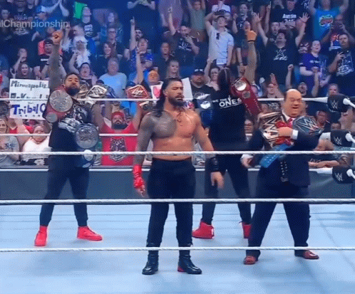A Group Of Wrestlers Are Standing In A Ring With Their Championship Belts GIF