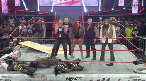 A Group Of Wrestlers Are Standing In A Wrestling Ring And One Of Them Is Wearing A Black Shirt With The Letter K On It GIF