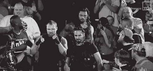 A Group Of Wrestlers Are Standing In Front Of A Crowd Of People . GIF