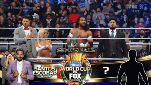 A Group Of Wrestlers Are Standing In Front Of A Sign That Says Smack Down World Cup On Fox GIF