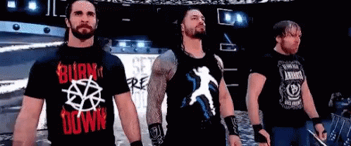 A Group Of Wrestlers Are Standing Next To Each Other On A Stage In Front Of A Crowd . GIF