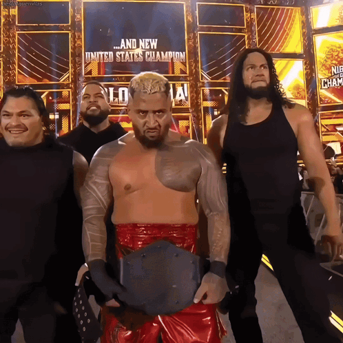 A Group Of Wrestlers Standing In Front Of A Sign That Says United States Champion GIF