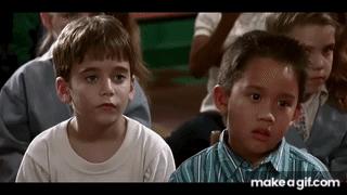 A Group Of Young Boys Are Sitting In A Classroom Looking At Something . GIF