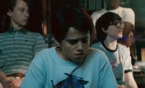 A Group Of Young Boys Are Sitting In A Room And One Of Them Is Wearing A Blue Shirt With A Bird On It . GIF