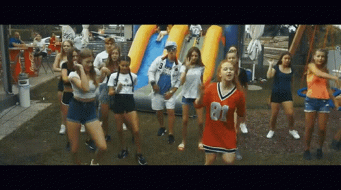 A Group Of Young Girls Are Dancing In Front Of A Coca Cola Cooler GIF