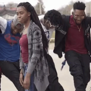 A Group Of Young Men And Women Are Walking Down The Street . GIF
