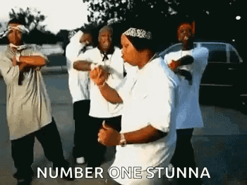 A Group Of Young Men Are Dancing In A Parking Lot And One Of Them Is Wearing A Bandana . GIF
