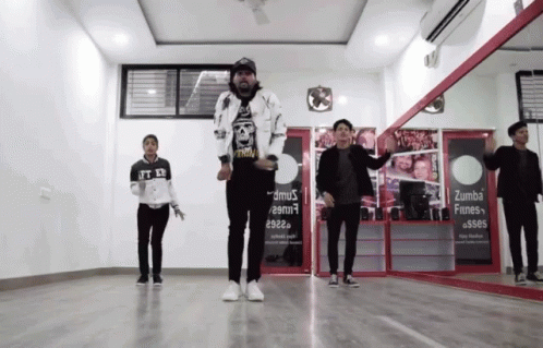 A Group Of Young Men Are Dancing In Front Of A Sign That Says Zumba Fines GIF