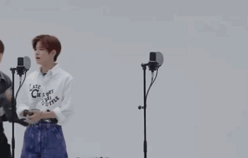 A Group Of Young Men Are Dancing In Front Of Microphones . GIF