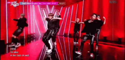 A Group Of Young Men Are Dancing On A Stage In Front Of A Red Curtain . GIF