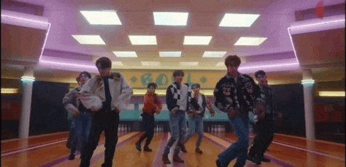 A Group Of Young Men Are Dancing Together In A Bowling Alley . GIF