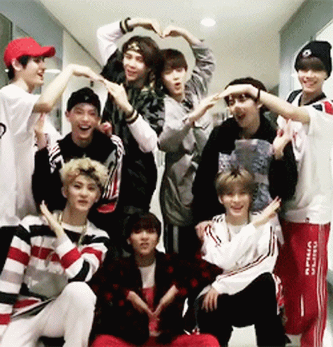 A Group Of Young Men Are Making A Heart Shape With Their Hands In A Hallway GIF