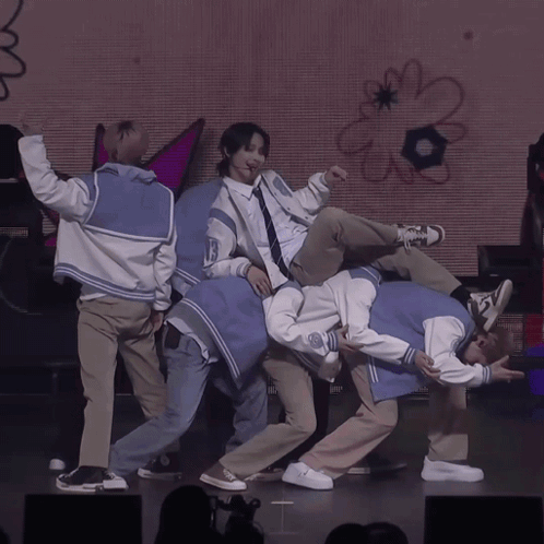 A Group Of Young Men Are Performing On A Stage With A Sign That Says Boom GIF