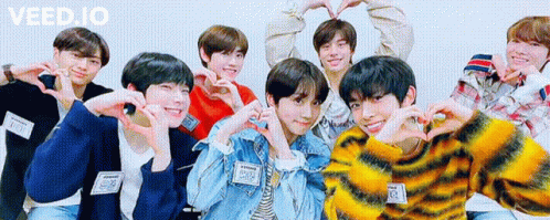 a group of young men are posing for a picture and making hearts with their hands .