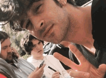 A Group Of Young Men Are Posing For A Picture While One Of Them Is Holding A Cell Phone In His Hand . GIF