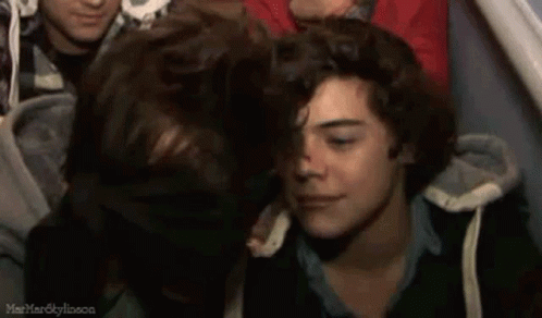 A Group Of Young Men Are Sitting Next To Each Other In A Crowd . GIF