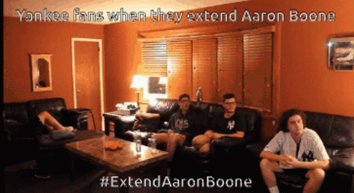 a group of young men are sitting on a couch in a living room watching a baseball game