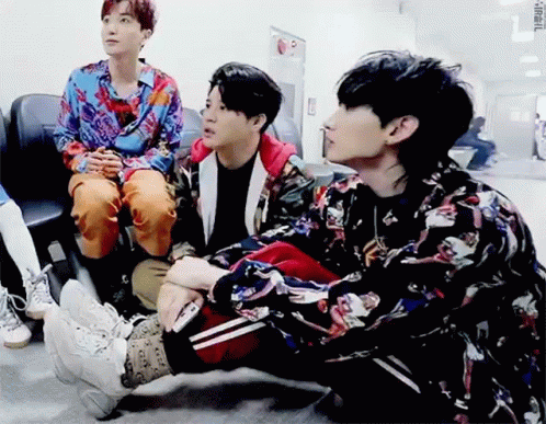 A Group Of Young Men Are Sitting On The Floor And Talking To Each Other . GIF