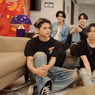 A Group Of Young Men Are Sitting On The Floor In Front Of A Couch .. GIF