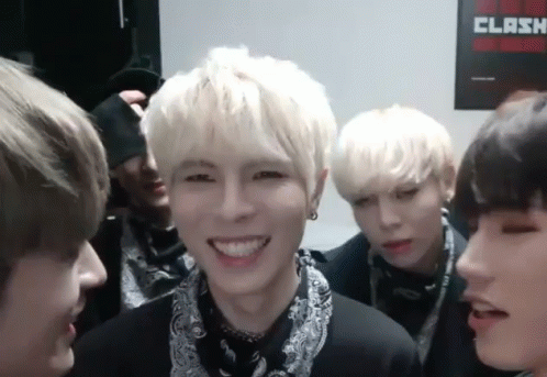 A Group Of Young Men Are Smiling In Front Of A Clash Poster On The Wall GIF