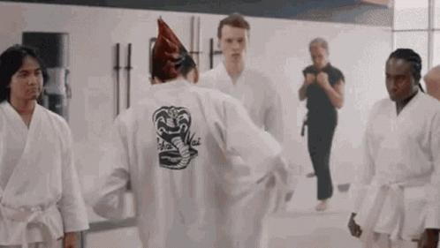 A Group Of Young Men Are Standing In A Gym Wearing Karate Uniforms . GIF