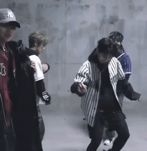 A Group Of Young Men Are Standing In A Room . GIF