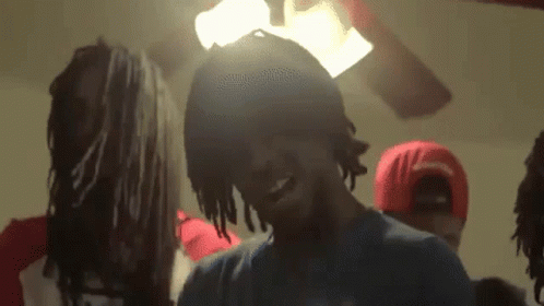A Group Of Young Men Are Standing In A Room With A Ceiling Fan . GIF