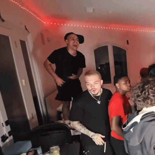 A Group Of Young Men Are Standing In A Room With A Red Light On The Ceiling GIF