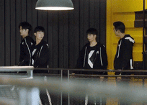 A Group Of Young Men Are Standing In Front Of A Yellow Wall . GIF