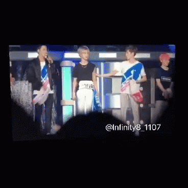 A Group Of Young Men Are Standing Next To Each Other And Looking At Each Other . GIF