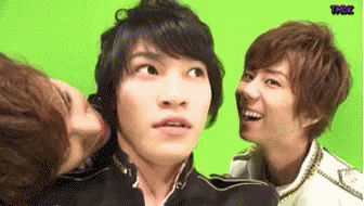A Group Of Young Men Are Standing Next To Each Other And One Of Them Is Kissing Another Man On The Cheek . GIF