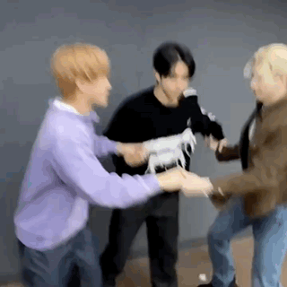 A Group Of Young Men Are Standing Next To Each Other Holding Hands While A Man Holds A Toy Horse . GIF