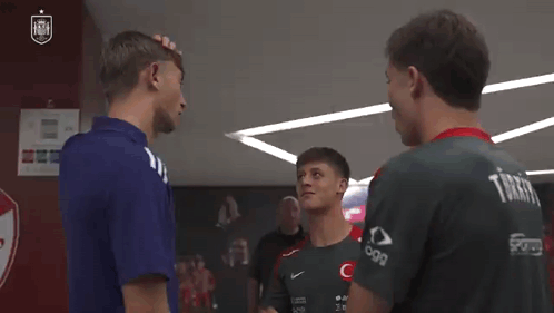 A Group Of Young Men Are Standing Next To Each Other In A Locker Room Talking To Each Other . GIF
