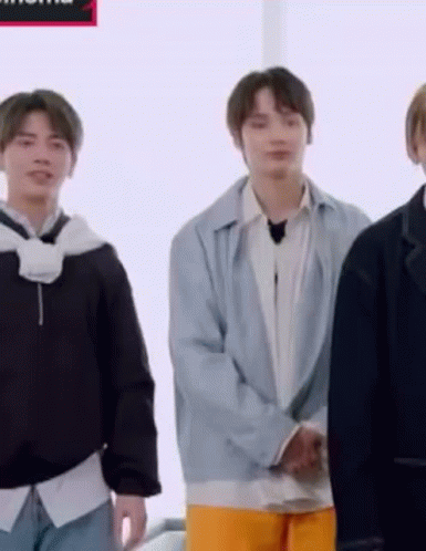 A Group Of Young Men Are Standing Next To Each Other In A Room And Smiling . GIF