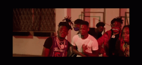 A Group Of Young Men Are Standing Next To Each Other In Front Of A Building . GIF