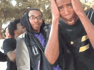 A Group Of Young Men Are Standing Next To Each Other With Their Hands On Their Head . GIF