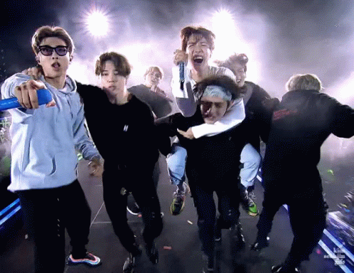 A Group Of Young Men Are Standing On A Stage Holding Microphones And Singing Into Them . GIF