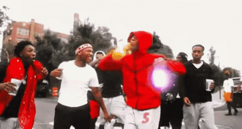 A Group Of Young Men Are Walking Down A Street . GIF