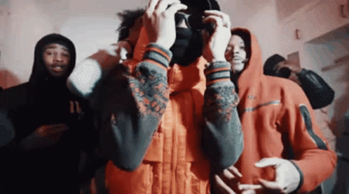 A Group Of Young Men In Hoodies Are Standing In A Room Taking A Picture With A Camera . GIF
