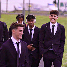 A Group Of Young Men In Suits And Ties Are Walking Together GIF