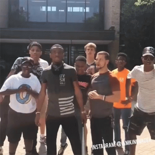 A Group Of Young Men Standing In Front Of A Building With One Man Wearing A Shirt That Says Ov Sn On It GIF