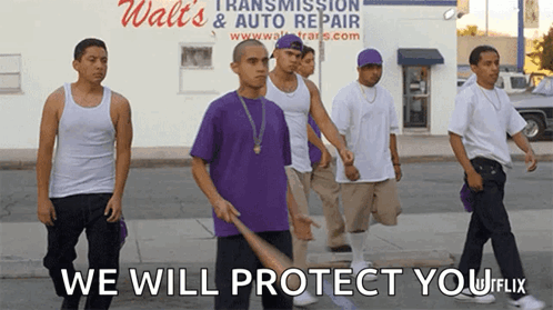 A Group Of Young Men Walking Down A Street With The Words " We Will Protect You " On The Bottom GIF