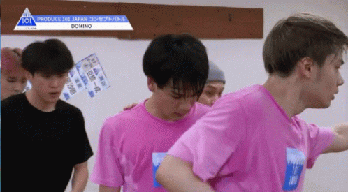 A Group Of Young Men Wearing Pink Shirts Are Standing In Front Of A Sign That Says Produce 101 Japan GIF