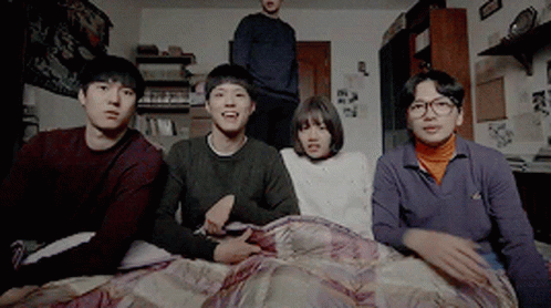 A Group Of Young People Are Sitting On A Bed Looking At Something GIF