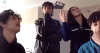 A Group Of Young People Are Standing In A Room With Their Arms Crossed . GIF
