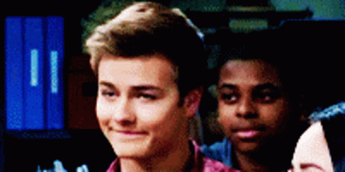 A Group Of Young People Are Standing Next To Each Other In A Room . GIF