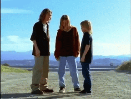 a group of young people are standing on a dirt road .
