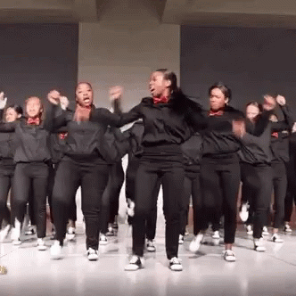 A Group Of Young Women Are Dancing Together On A Stage In A Room . GIF
