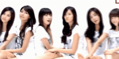 A Group Of Young Women Are Sitting In A Row With One Wearing A Shirt That Says ' A ' On It GIF