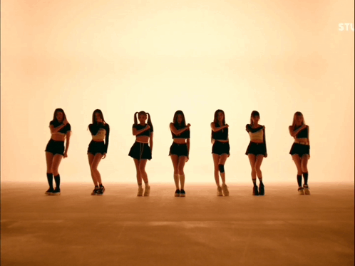 A Group Of Young Women Are Standing In A Row With Their Arms Crossed GIF